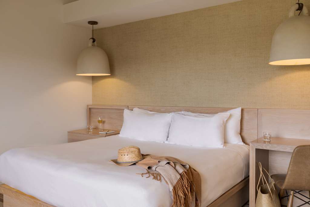 A hotel room with a large bed and end tables
