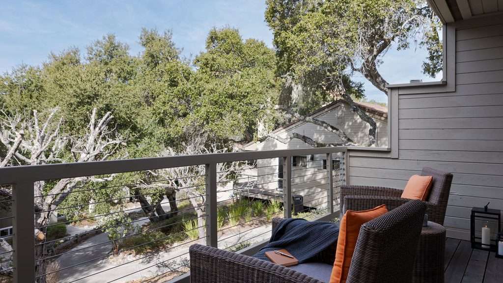 A balcony with armchairs and view of large trees