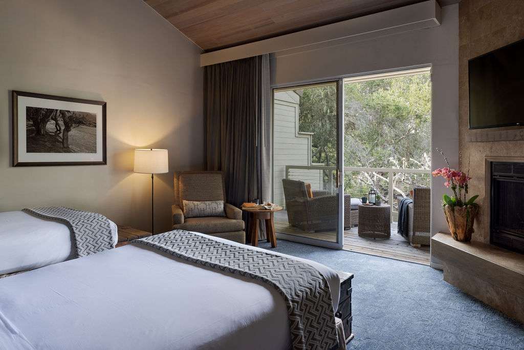 A hotel room with 2 beds and door to balcony