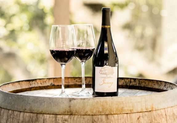 Two glasses of red wine and bottle on barrel