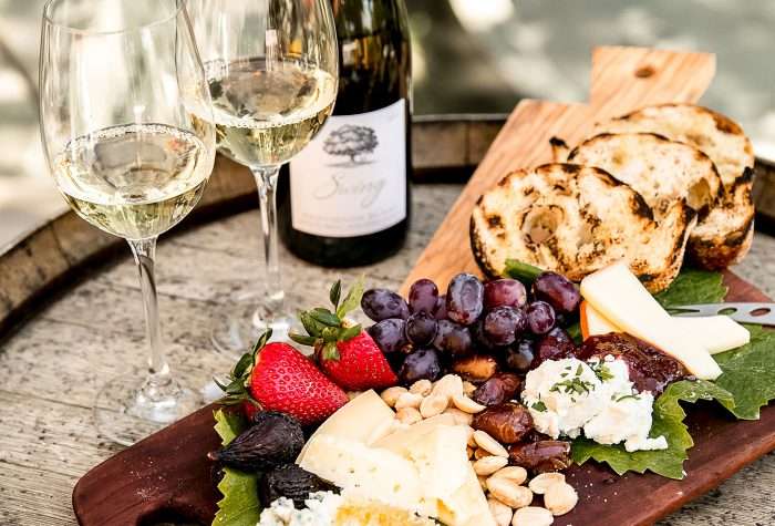 Cheese plate with fruit and glasses of white wine