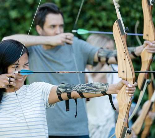 a woman and a man focusing at a target holding a classic curve bow during archery activity at Carmel Valley Ranch