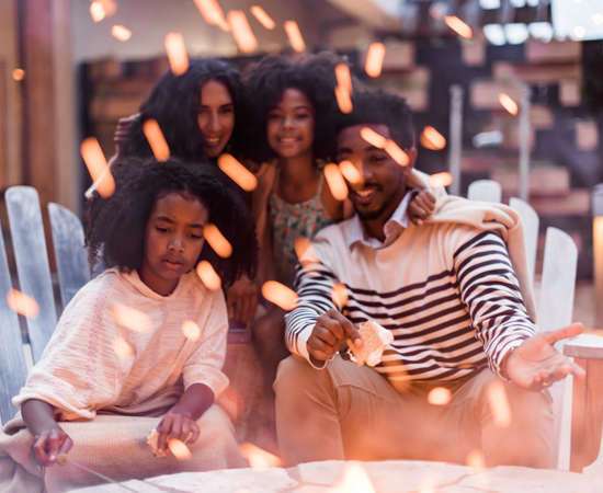 family of four people, a man and a woman and two kids roasting marshmallow at an outdoor fire pit at Carmel Valley Ranch
