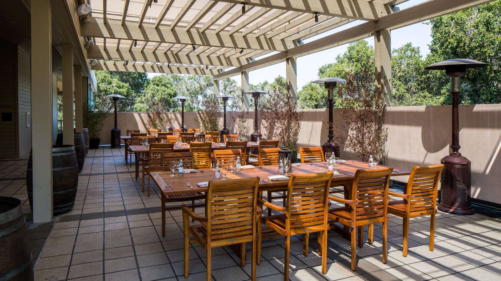 outdoor patio at day time with wooden tables and heaters along the wall, wooden roof at Carmel Valley Ranch