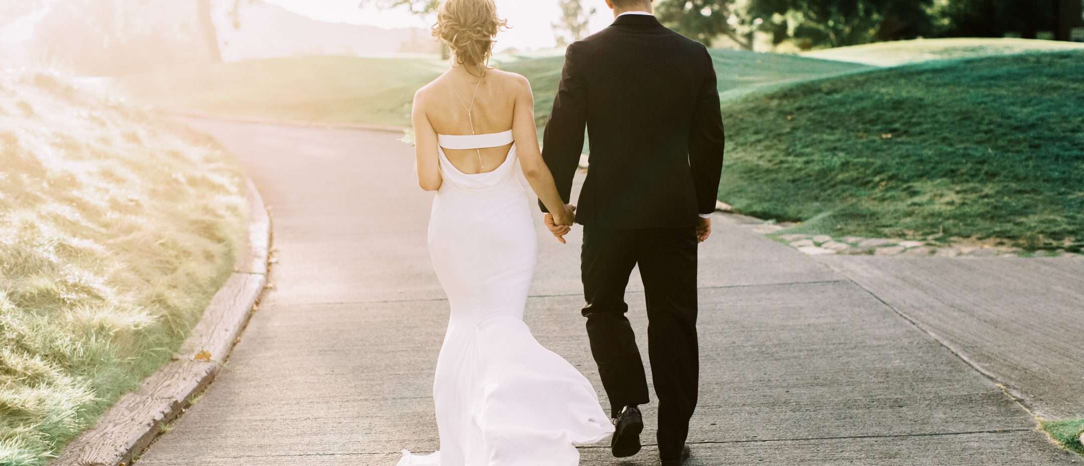 Bride and groom walking away from camera holding hands at Carmel Valley Ranch
