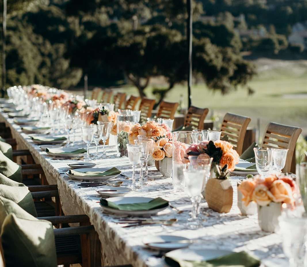 Long table set for guests at Carmel Valley Ranch with orange flower pieces