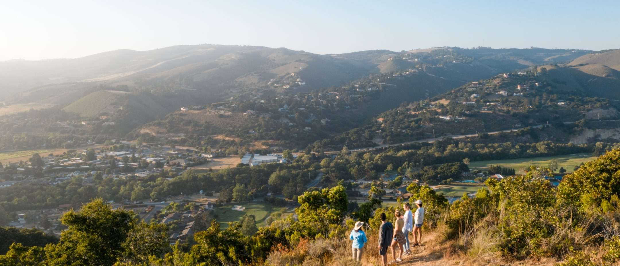 Group on path on top of mountain looking at the view of Carmel Valley on a sunny day
