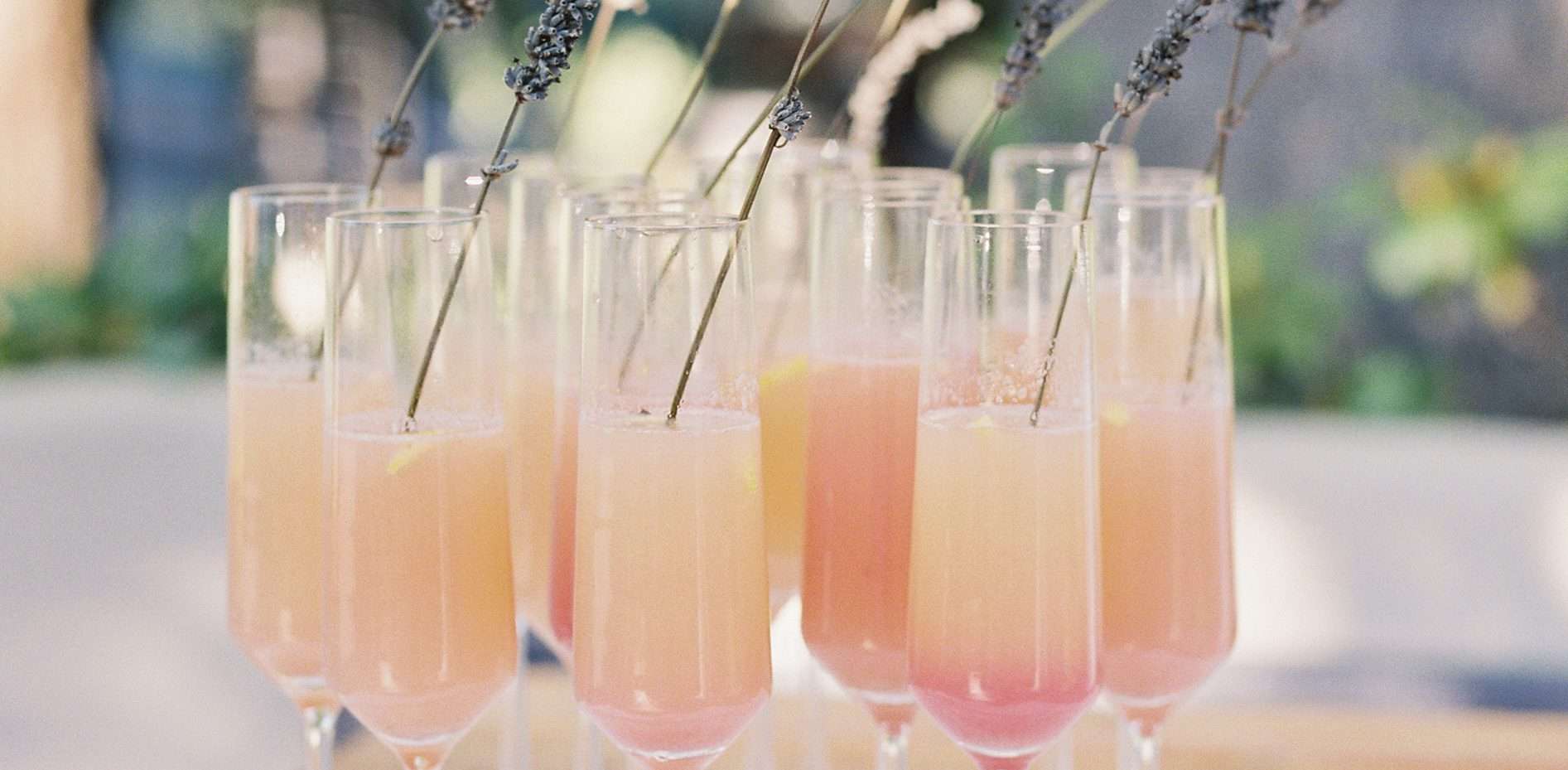 Group of pink drinks in champagne flutes on a white table with plants