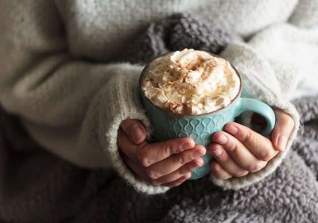 Hands holding hot chocolate with cream