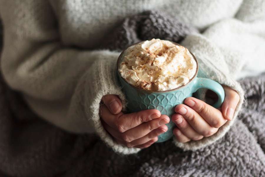 Hands holding hot chocolate with cream