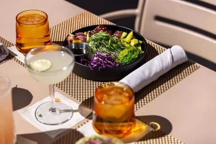 bowl of salad with drink setting at table