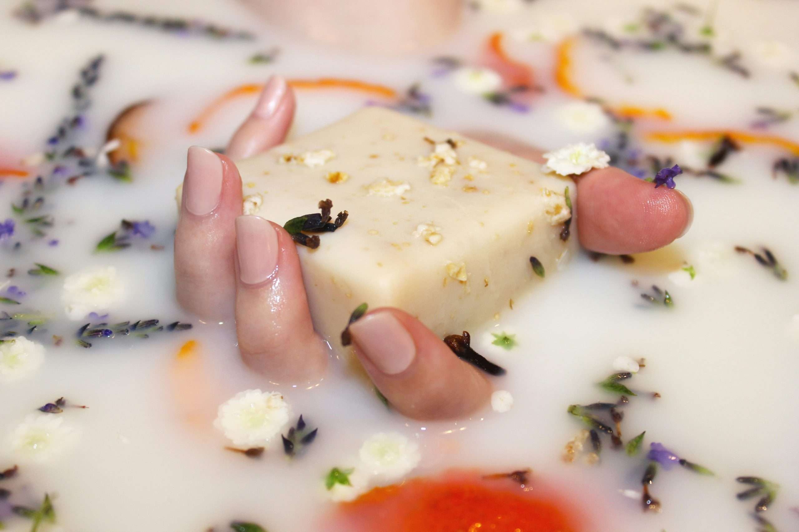 hand holding soap in milk bath